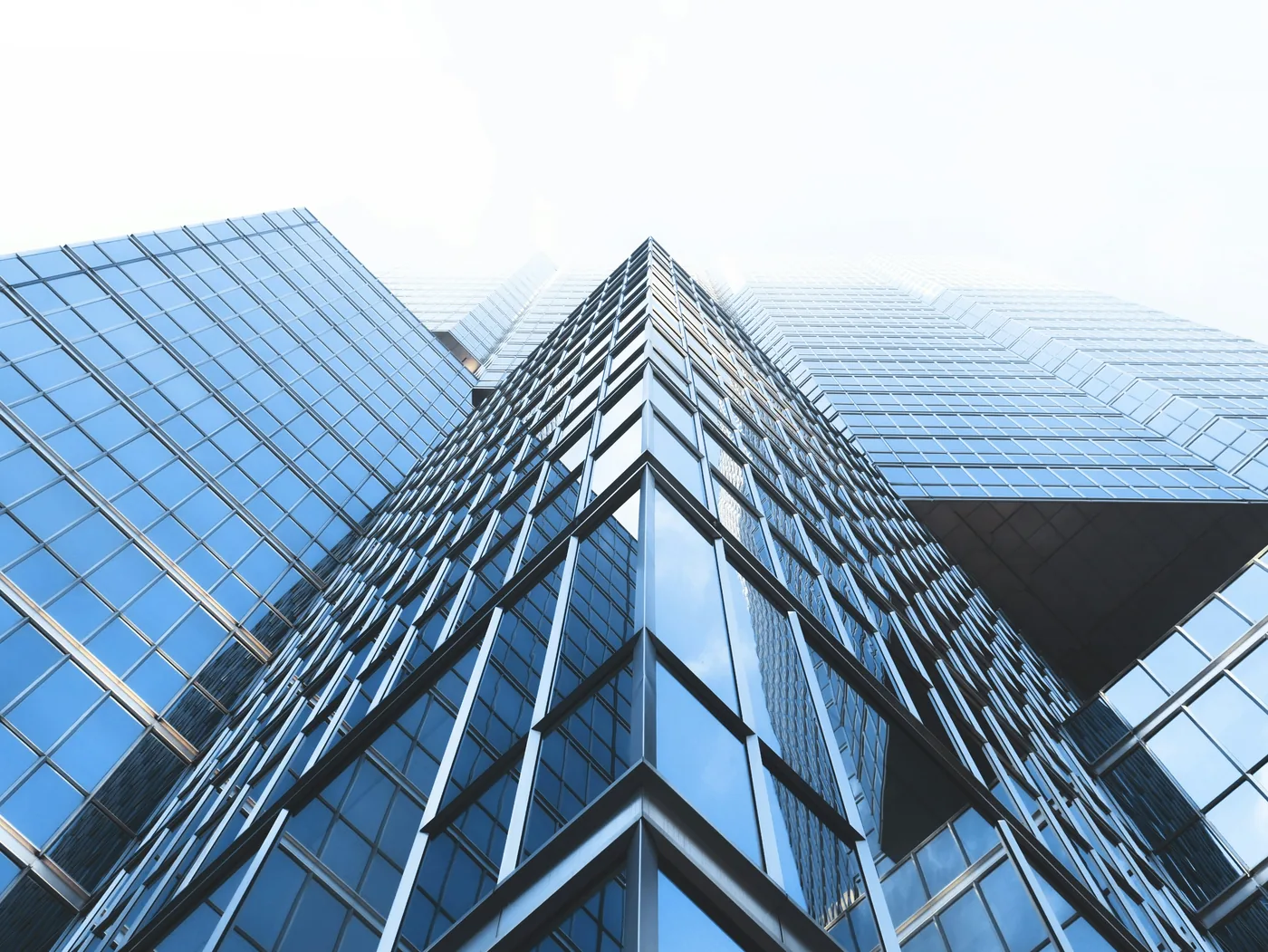 Glass skyscraper facade seen from below against a cloudy sky