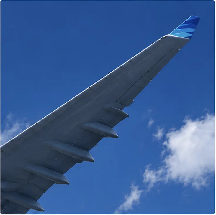 Punta del ala de un avión contra un cielo azul con nubes