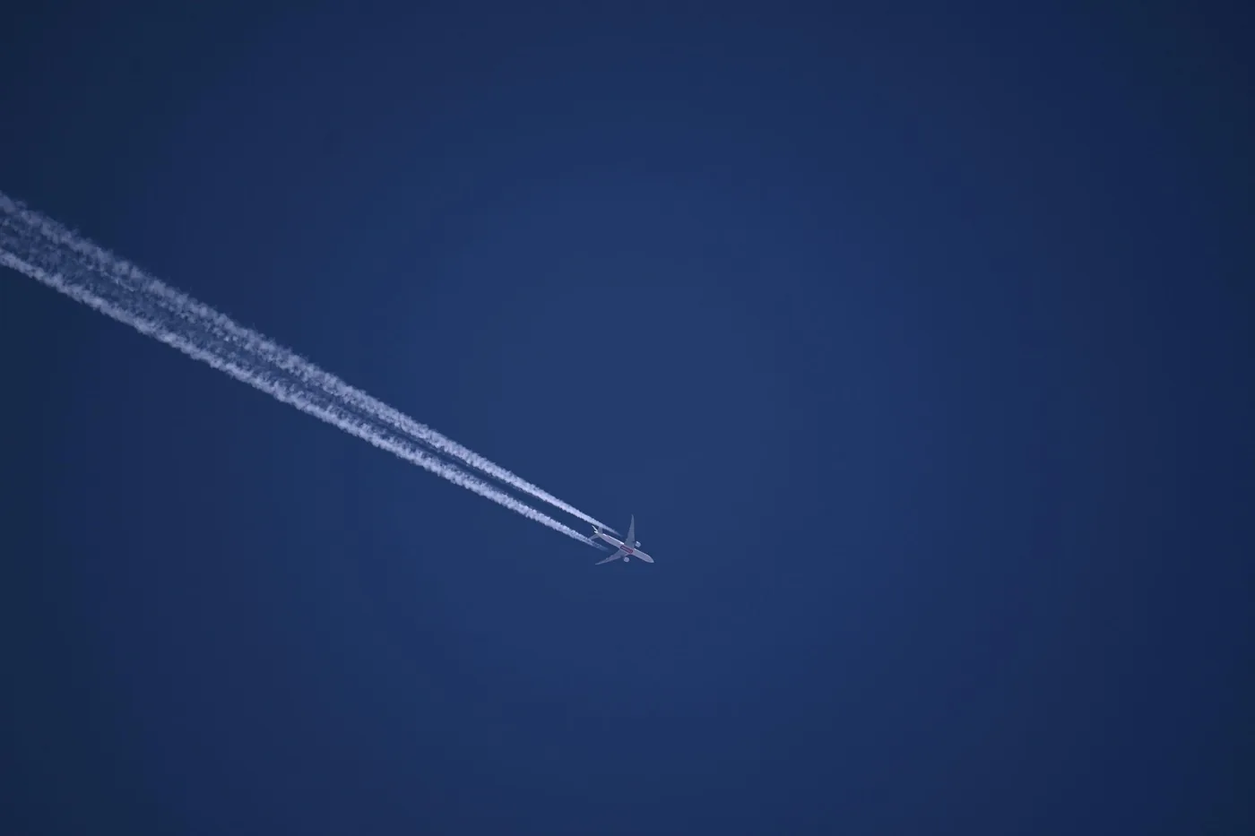 Avión volando a gran altitud dejando una estela de condensación en el cielo